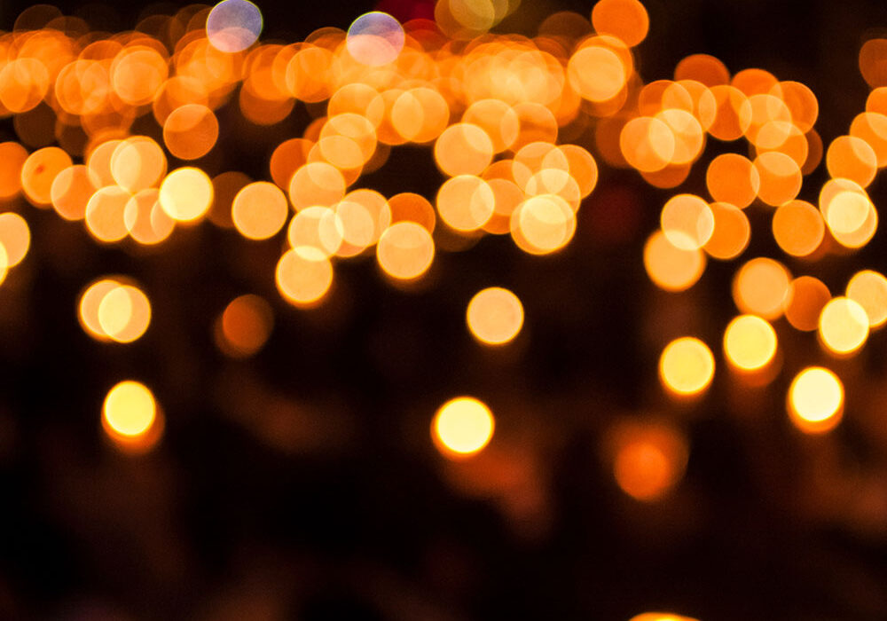 Warm orange bokeh lights in a dark scene, resembling a sea of candles at night fall of glow